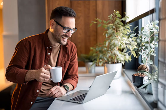 A man enjoying coffee and a computer.
