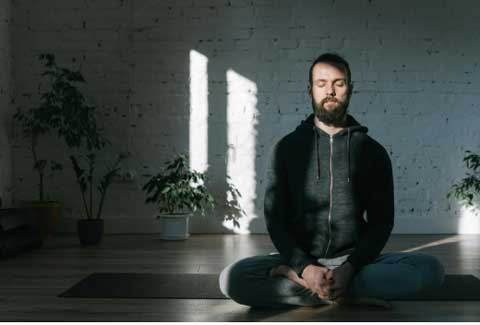 A man sitting cross legged on the floor apparently meditating