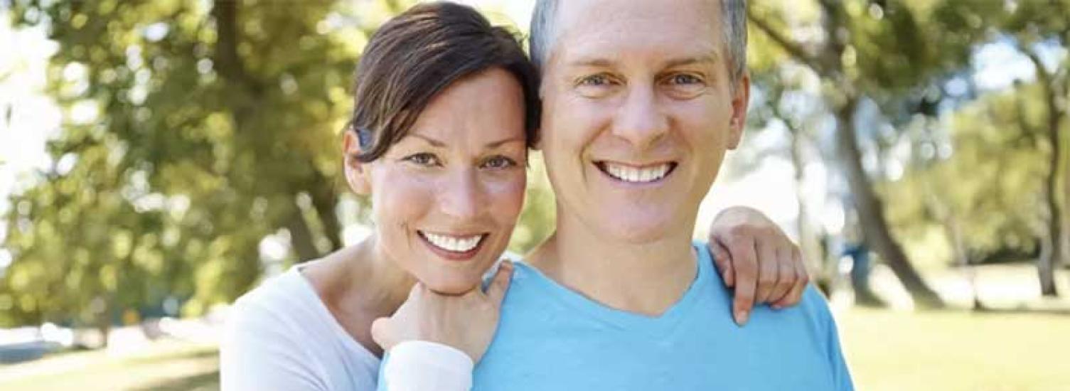 An affectionate couple, outside and smiling into the camera.